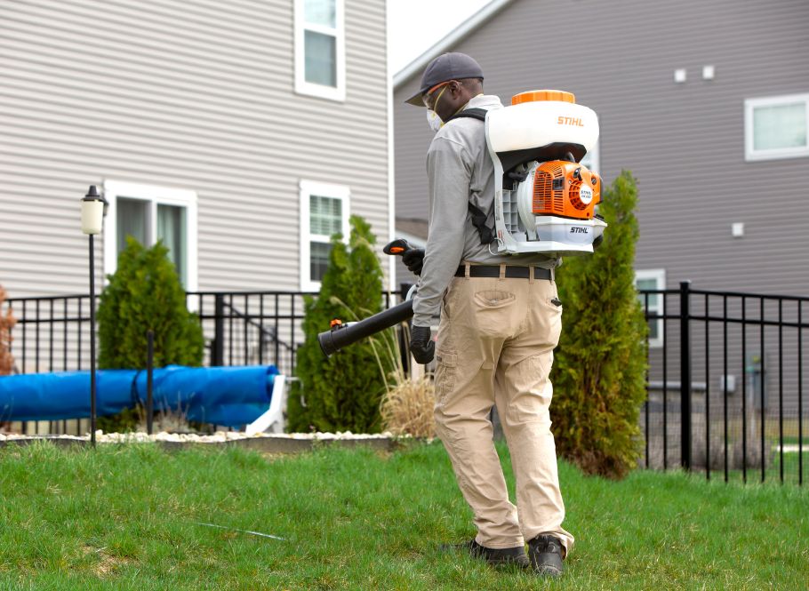 Fall pest control champion pest & termite control technician spraying outside house